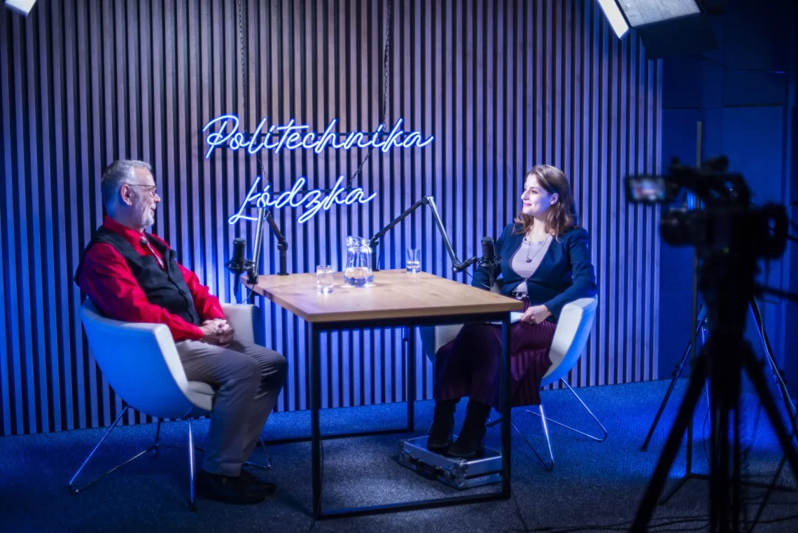 Kobieta w ciemnej garsonce rozmawia w studio nagraniowym z mężczyzną w czerwonej koszuli i kamizelce