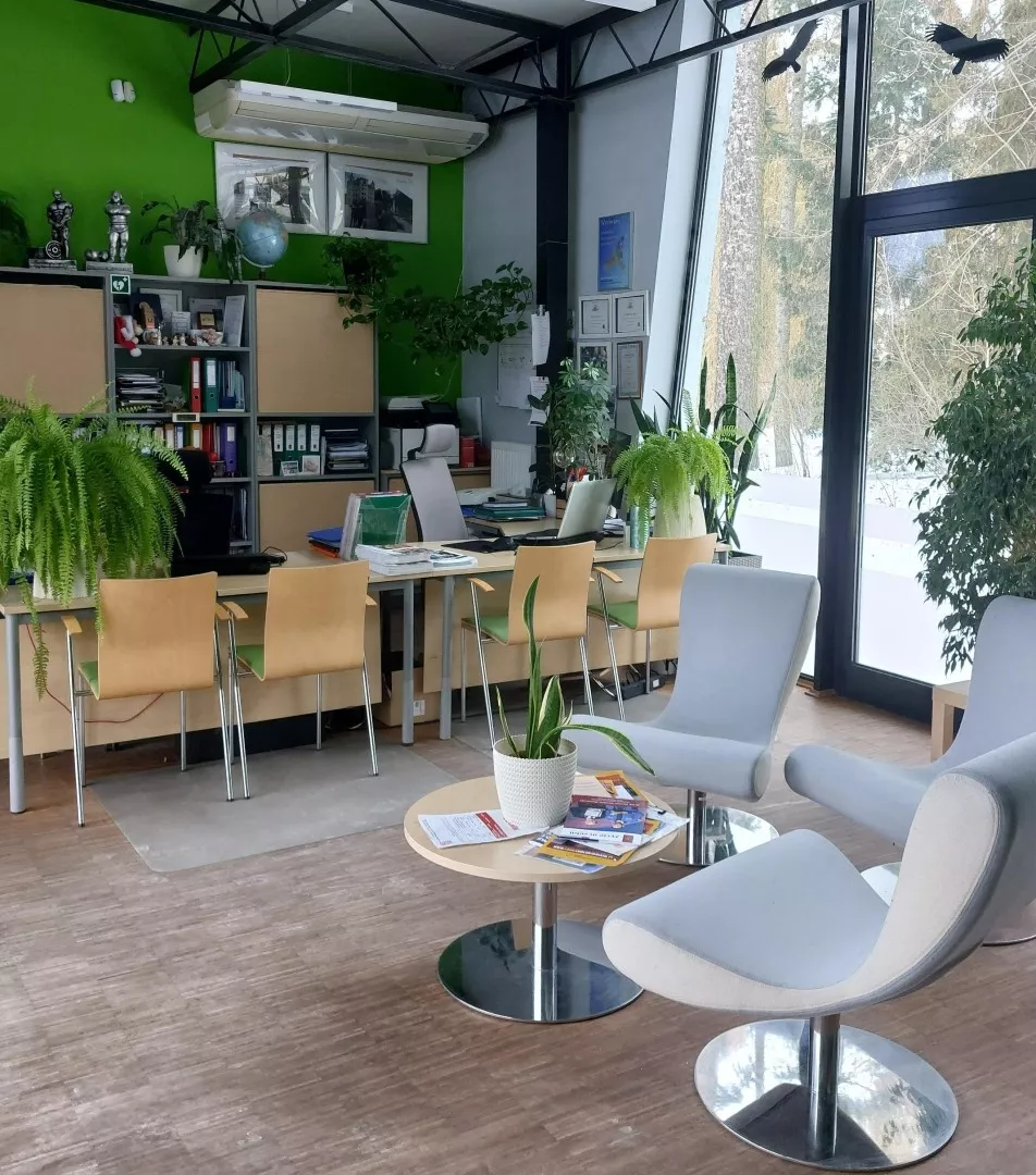 pomieszczenie ze stanowiskami do pracy biurowej oraz stolikiem i dwoma fotelami