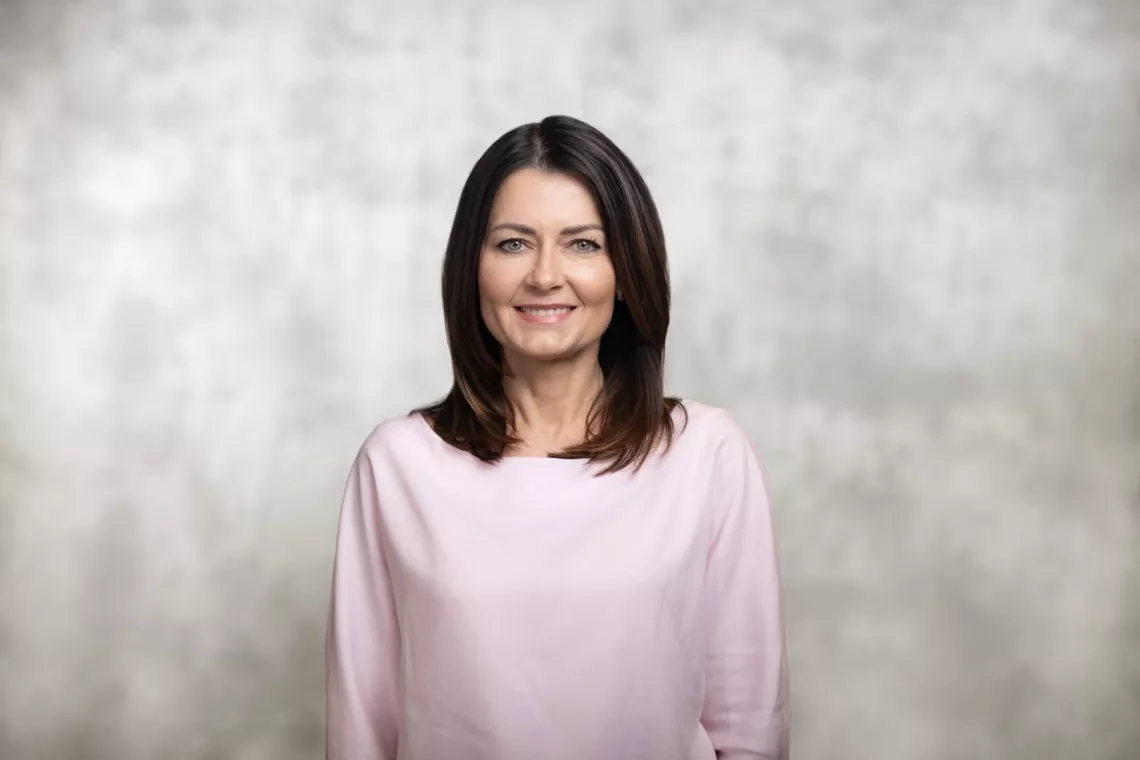 Uśmiechnięta kobieta z ciemnymi włosami rozpuszczonymi na ramion