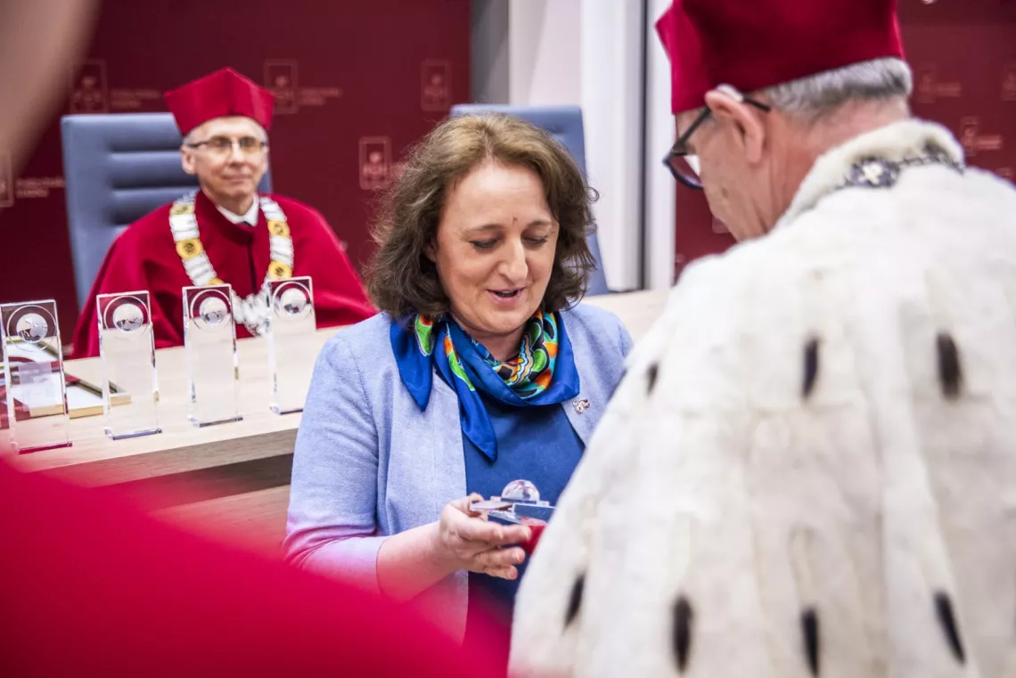 Kobieta odbiera nagrodę z rąk rektora