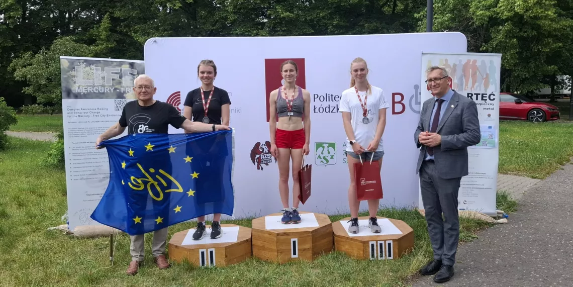 Trzy kobiety stoja na podium, obok dwaj mężczyźni, którzy składali gratulacje