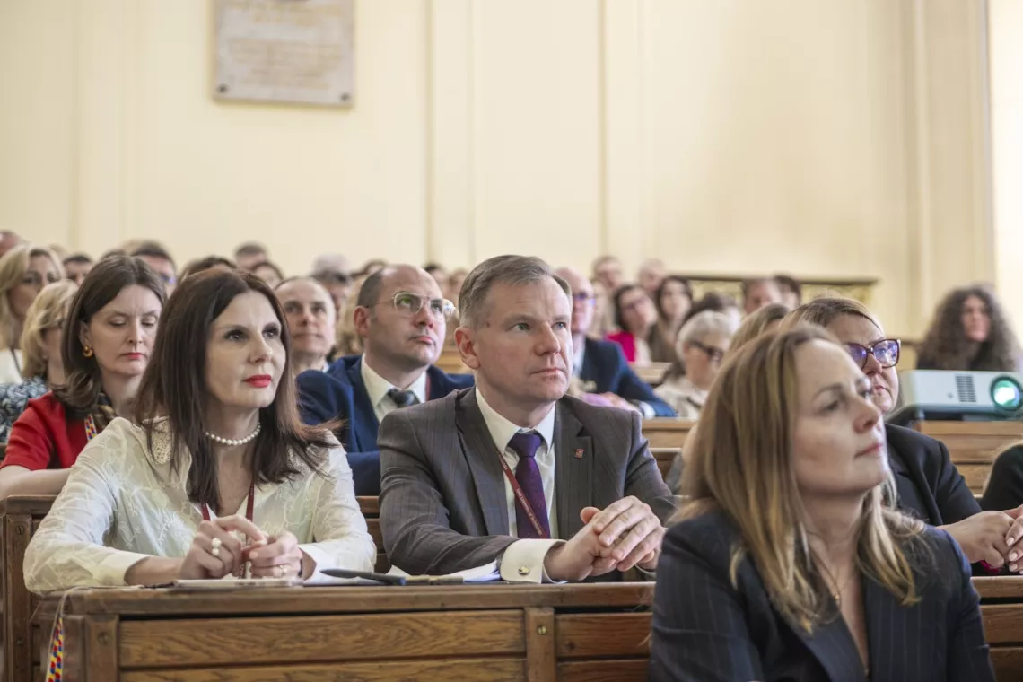 Grupa uczestników spotkania siedzi w audytorium.