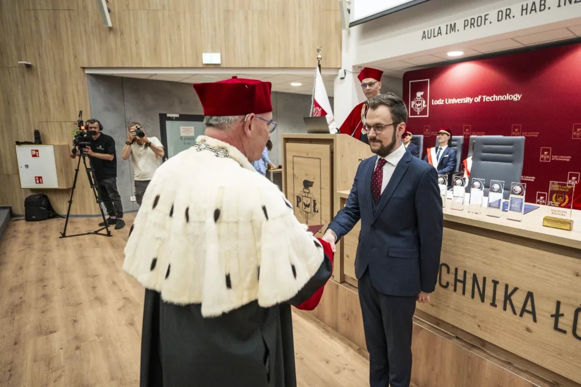 Młody mężczyzna odbiera gratulacje od JM Rektora 