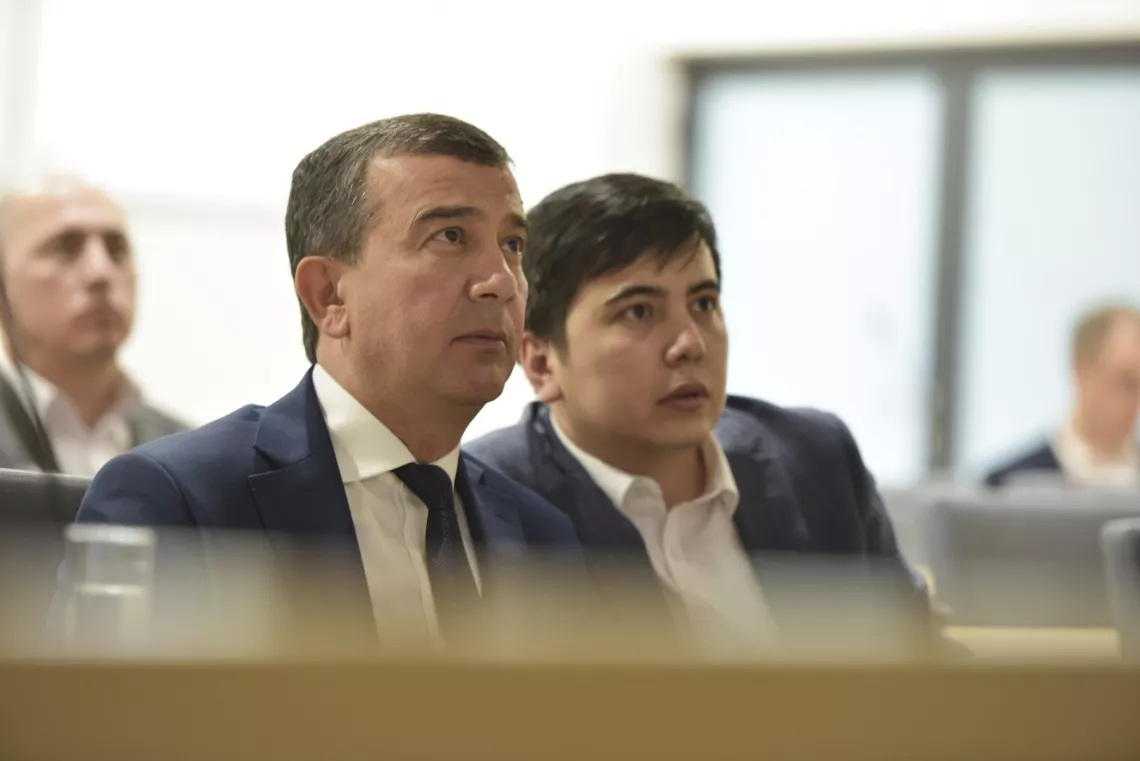 Dwóch elegancko ubranych mężczyzn słucha wystąpienia