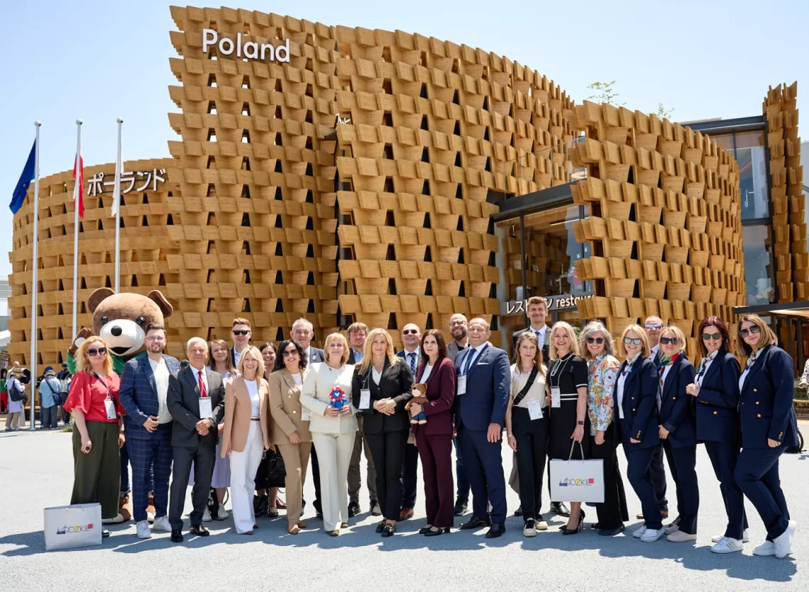 Liczna grupa osób stoi przed budyniem z napisem Poland