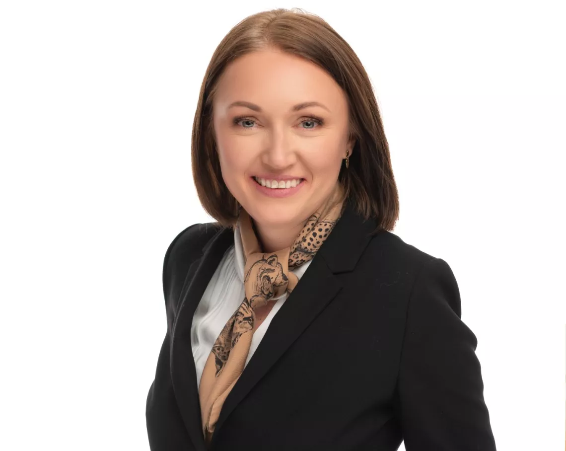 Uśmiechnięta kobieta w marynarce, z apaszką przy szyi