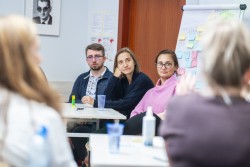 Uczestnicy szkolenia w sali seminaryjneh, w tle tablica z naklejonymi róznokolorowymi karteczkami