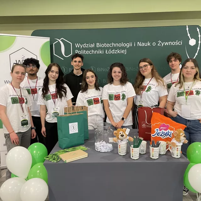 Studenci w koszulkach z napisem BINOŻ stoją przed stołem, na którym jest dużo róznych rzeczy